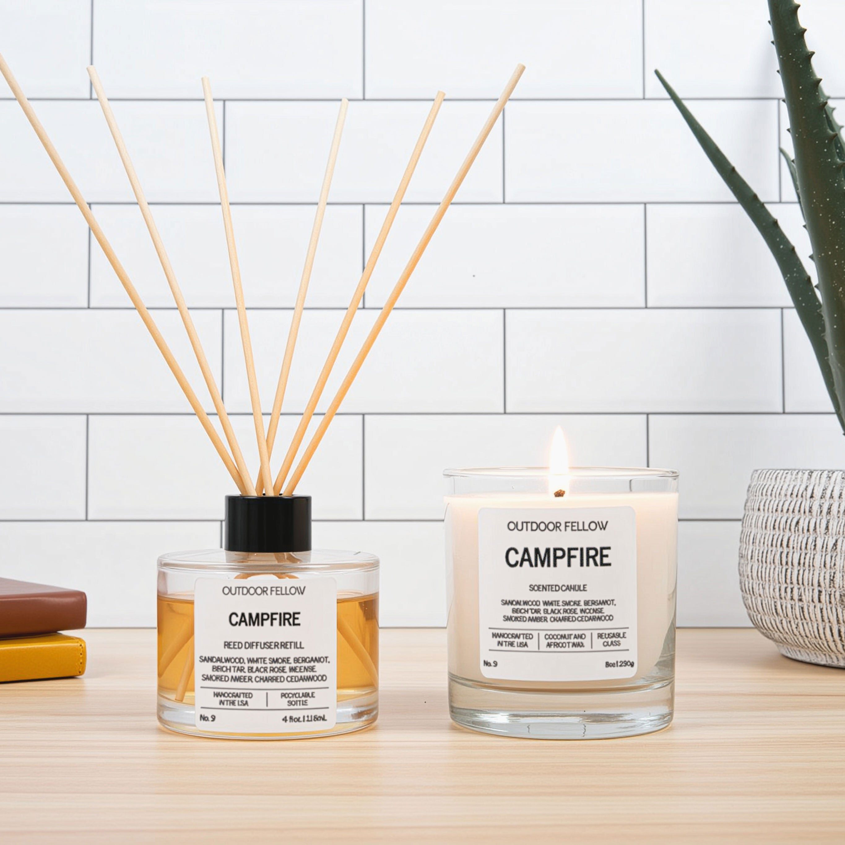 Outdoor Fellow' campfire-themed candles and reed diffuser on a wooden surface with a white tiled wall background.