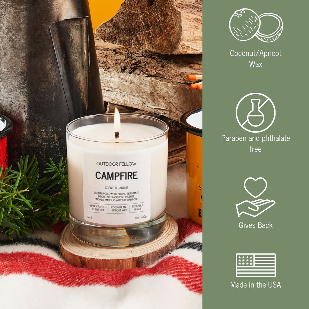 Candle labeled 'Campfire' by Outdoor Fellow with coconut/apricot wax, paraben and phthalate free, gives back, and made in the USA on a wooden coaster.