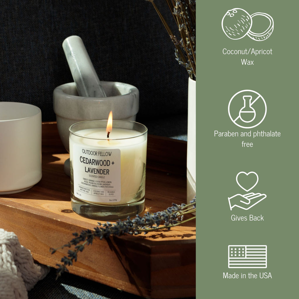 Candle with a label on a wooden surface, surrounded by decorative elements with text that says coconut/apricot wax, paraben and phthalate free, gives back and made in the USA. 