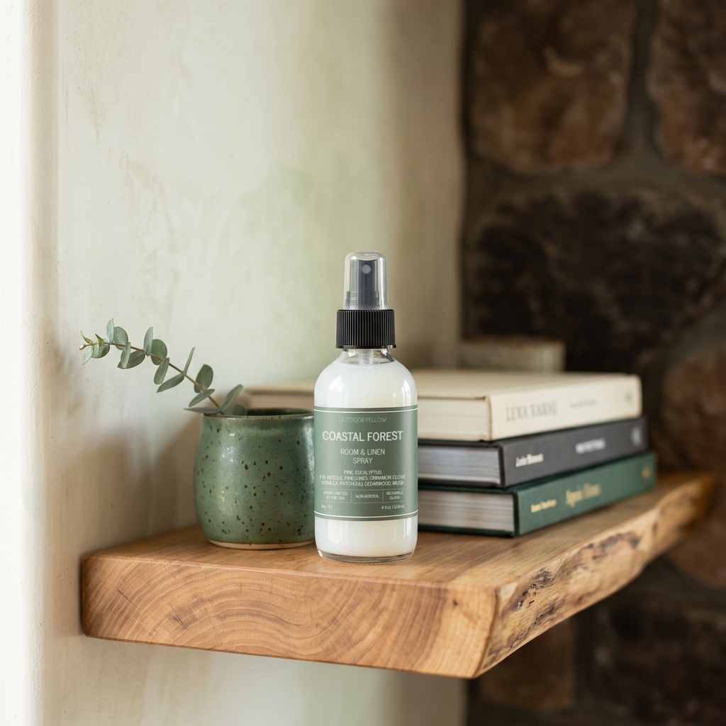 Outdoor Fellow Coastal Forest Room & Linen Spray styled on a natural wood shelf with books and eucalyptus.