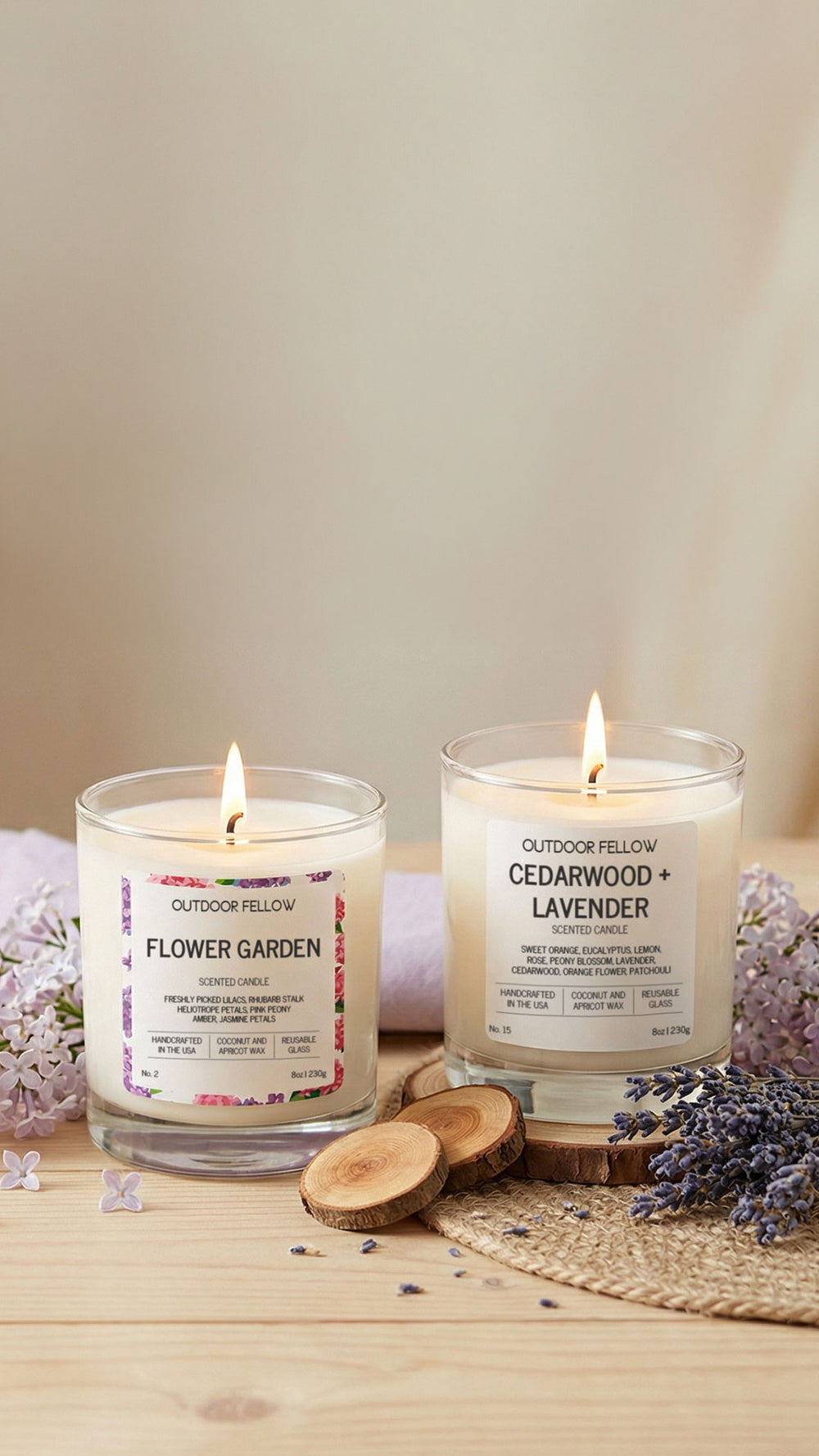 Two lit candles labeled 'Flower Garden' and 'Cedarwood + Lavender' on a wooden surface with lavender flowers.