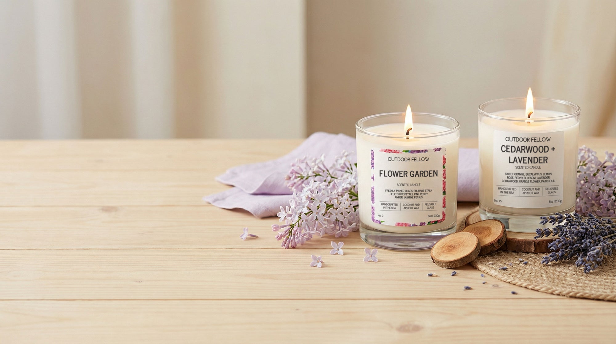 Two lit candles on a wooden surface with lavender flowers and wood slices.