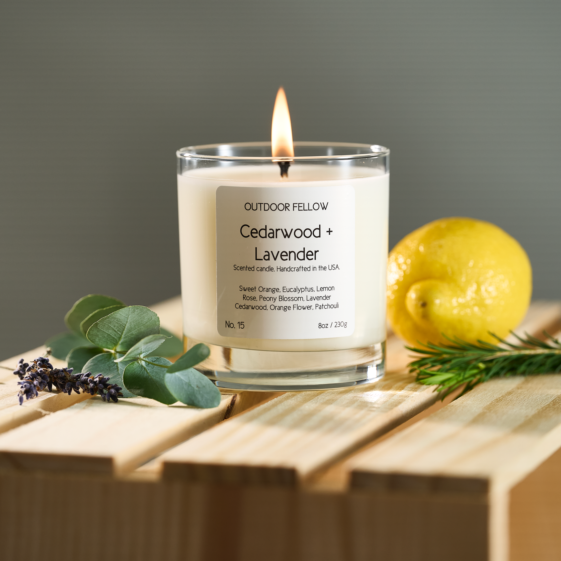 Cedarwood and Lavender scented candle on a wooden crate surrounded by lavender, eucalyptus and lemon