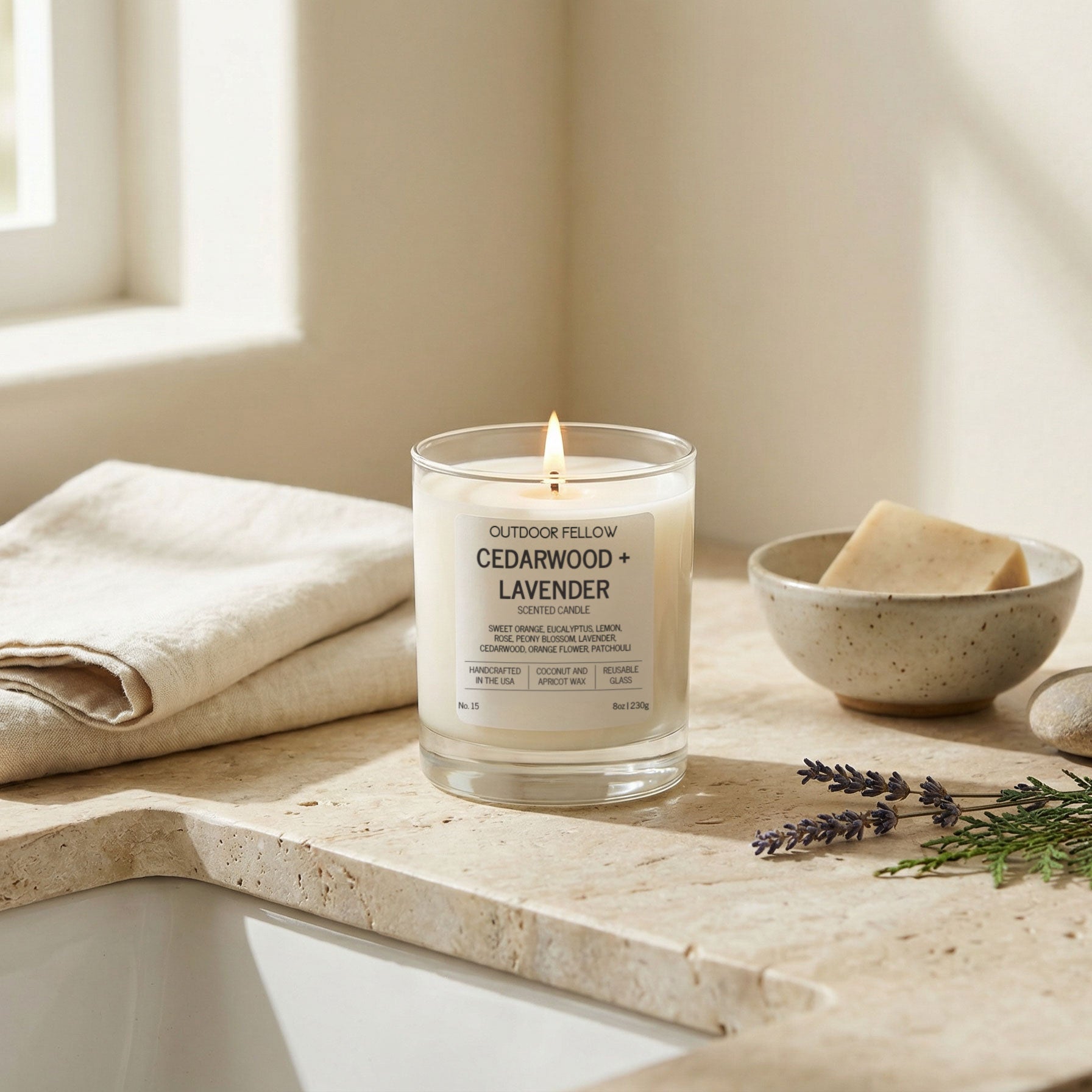 Candle labeled 'Cedarwood + Lavender' on a stone surface with a bowl and towel in the background.