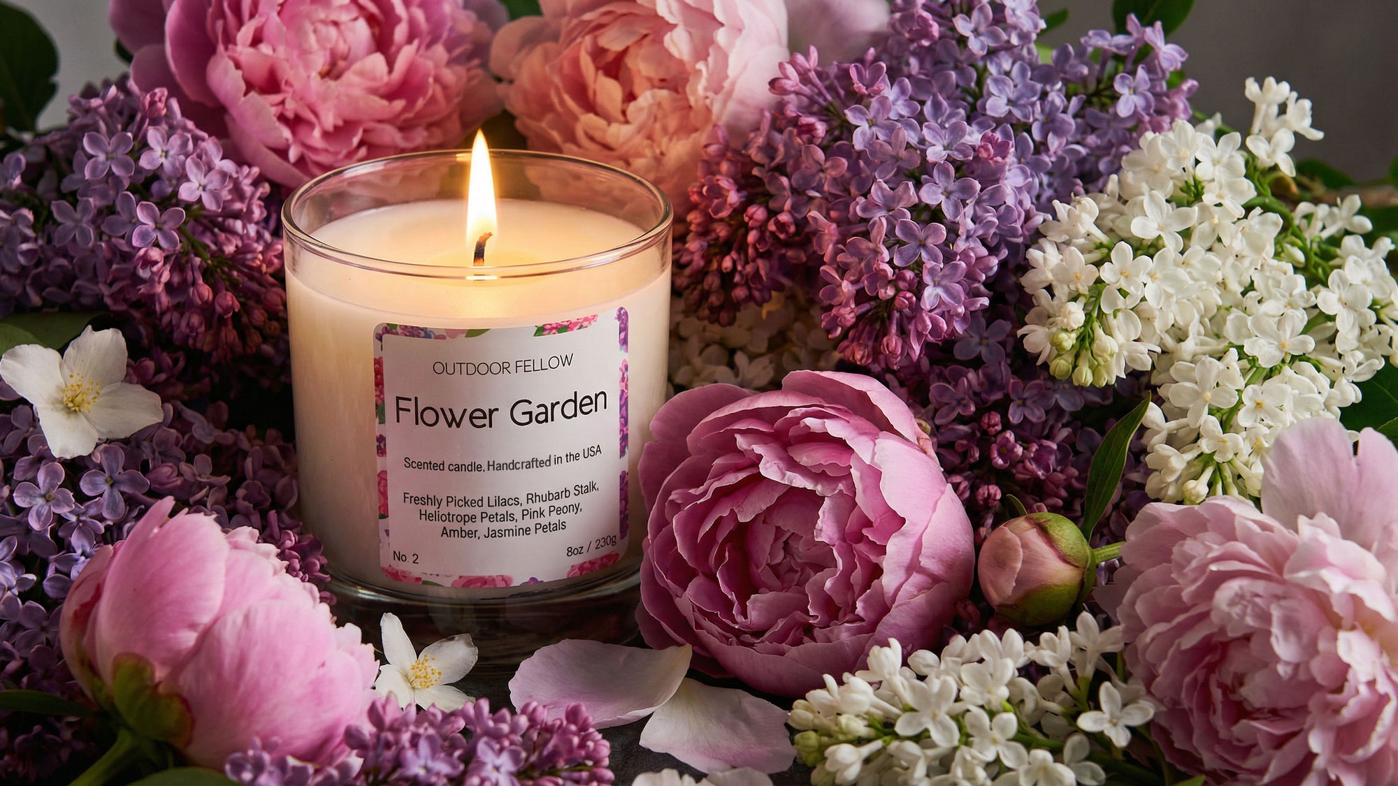 Candle labeled 'Flower Garden' surrounded by pink, purple, and white flowers.