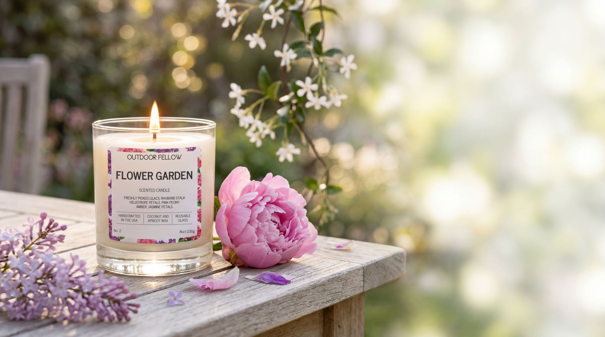 Candle labeled 'Flower Garden' on a table with flowers in an outdoor setting