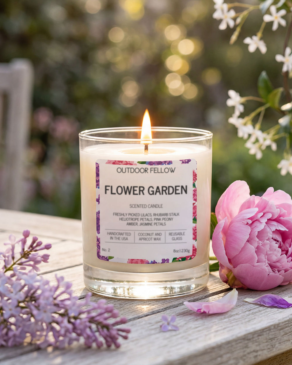 Flower Garden scented candle by Outdoor Fellow with flowers around on a wooden surface.