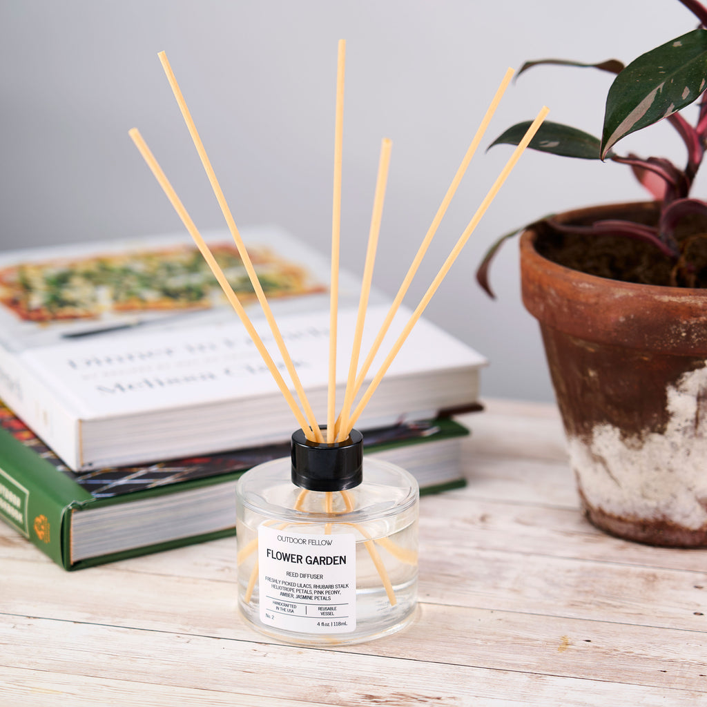 Flower Garden reed diffuser on a desk in front of books and a potted plant