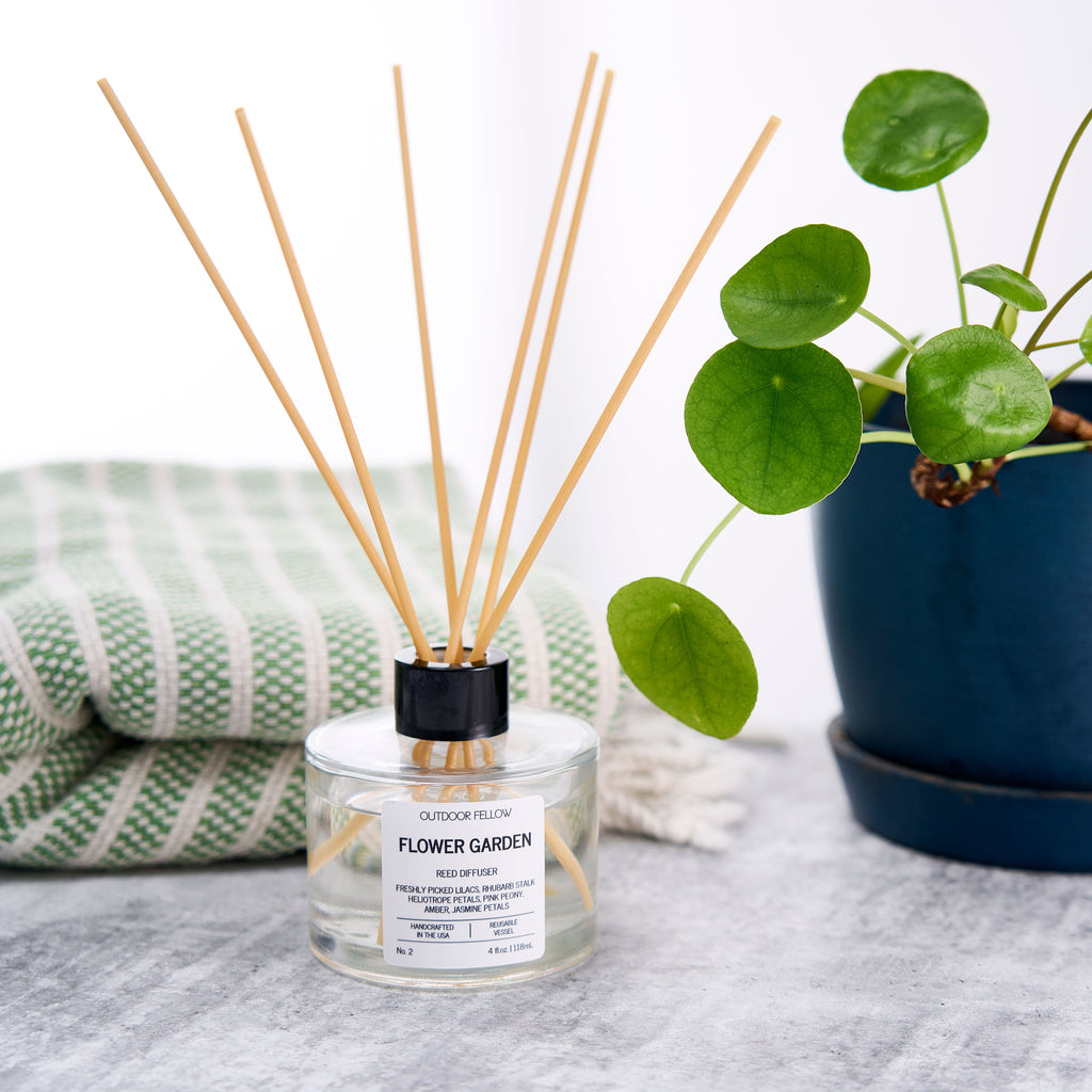Flower Garden reed diffusers on a concrete surface next to a plant and towel