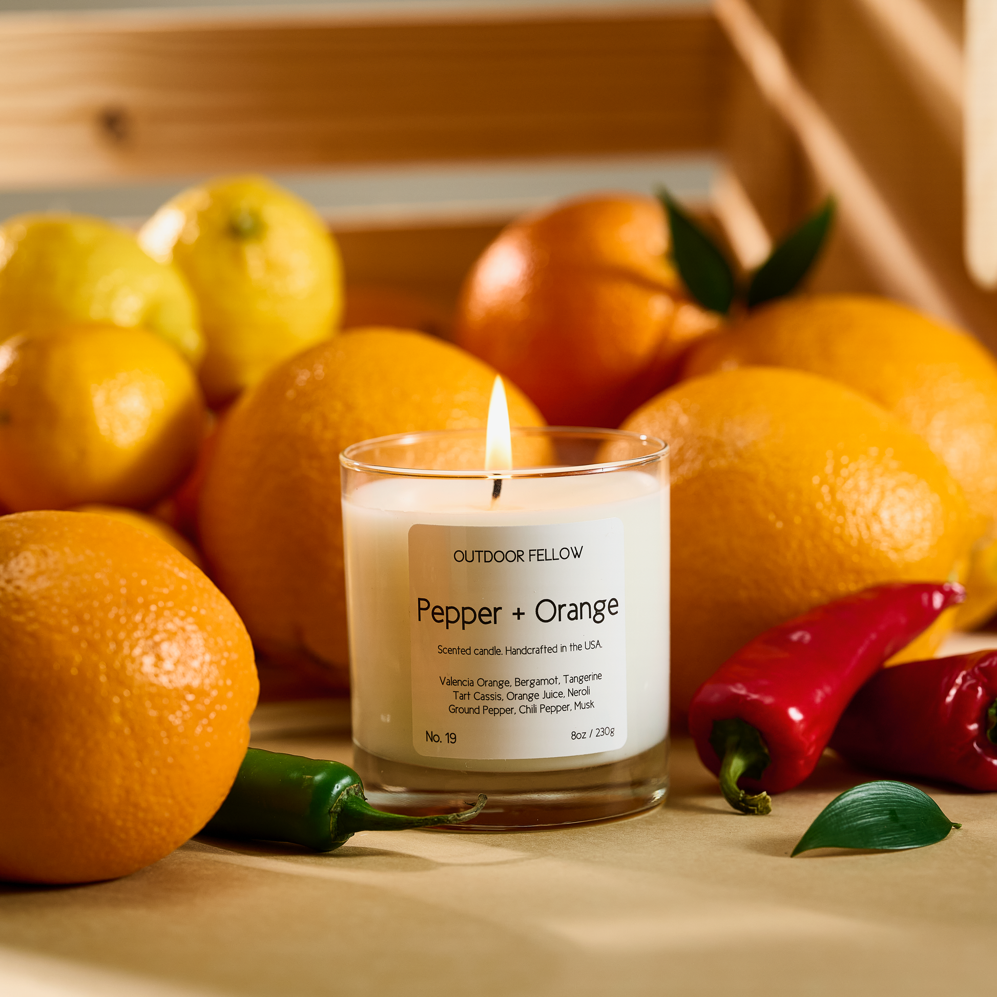 Pepper and Orange scented candle surrounded by oranges, lemons and chili peppers
