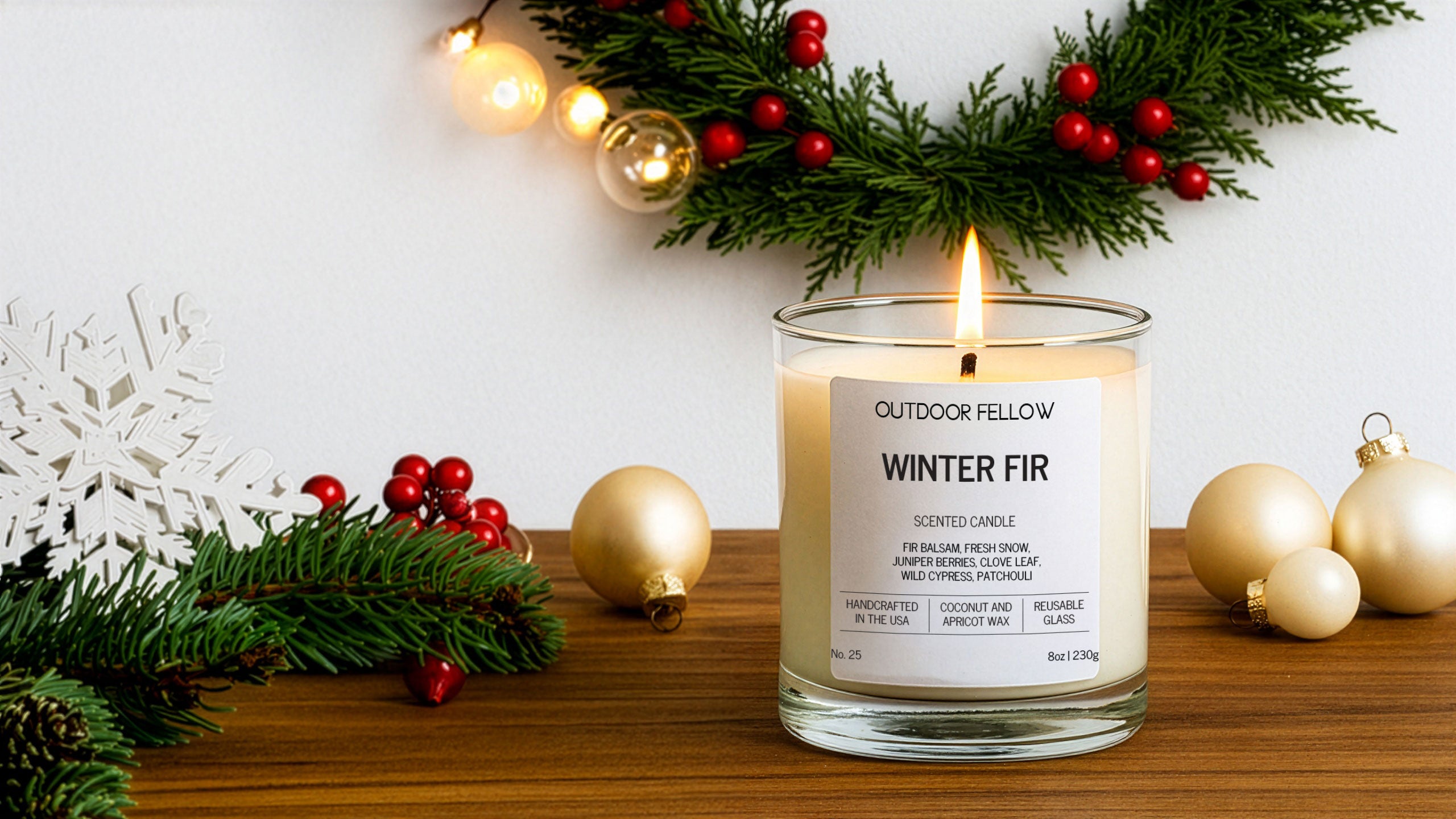 Candle labeled 'Winter Fir' from 'Outdoor Fellow' on a wooden surface with Christmas decorations.