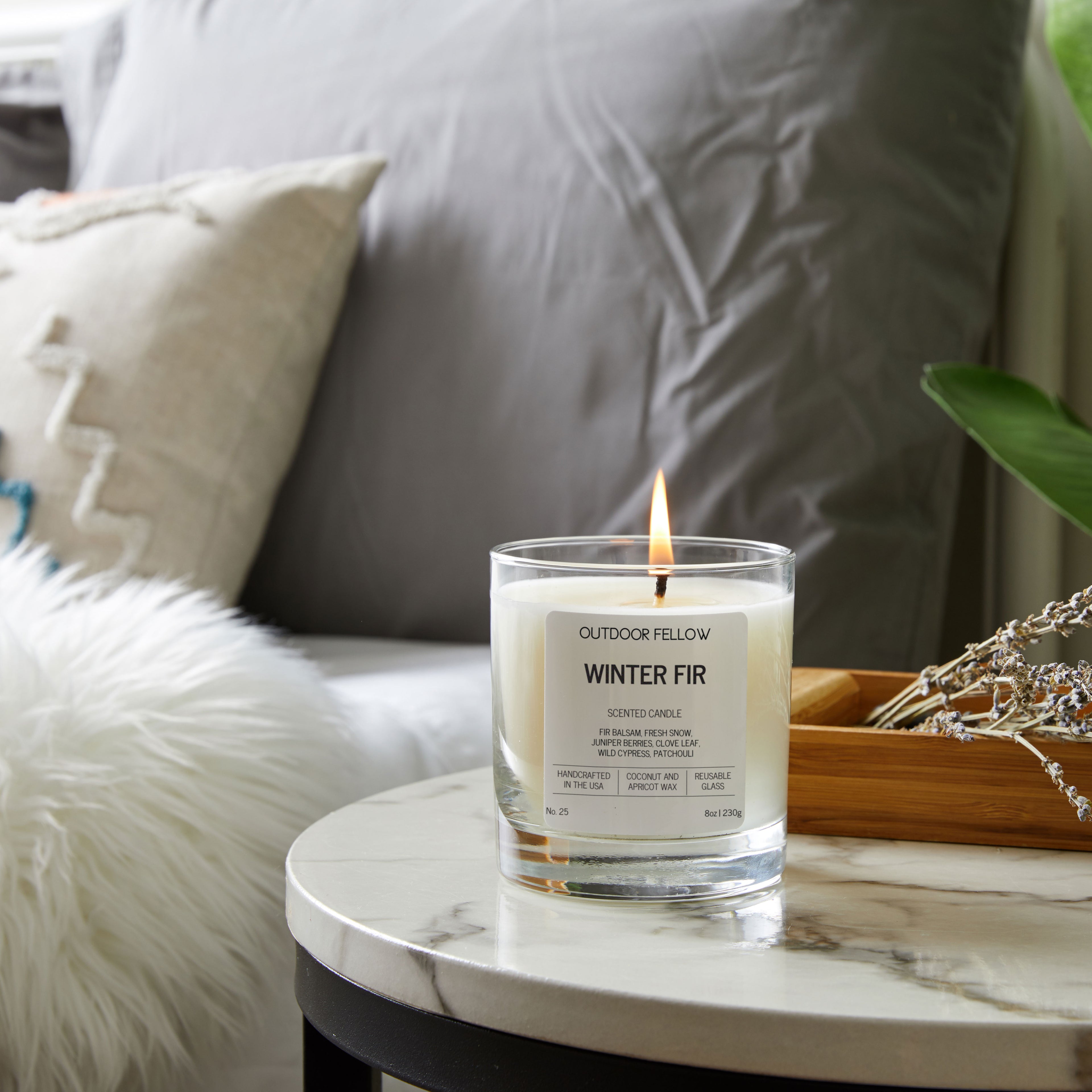 Candle labeled 'Winter Fir' on a marble table with a cozy background