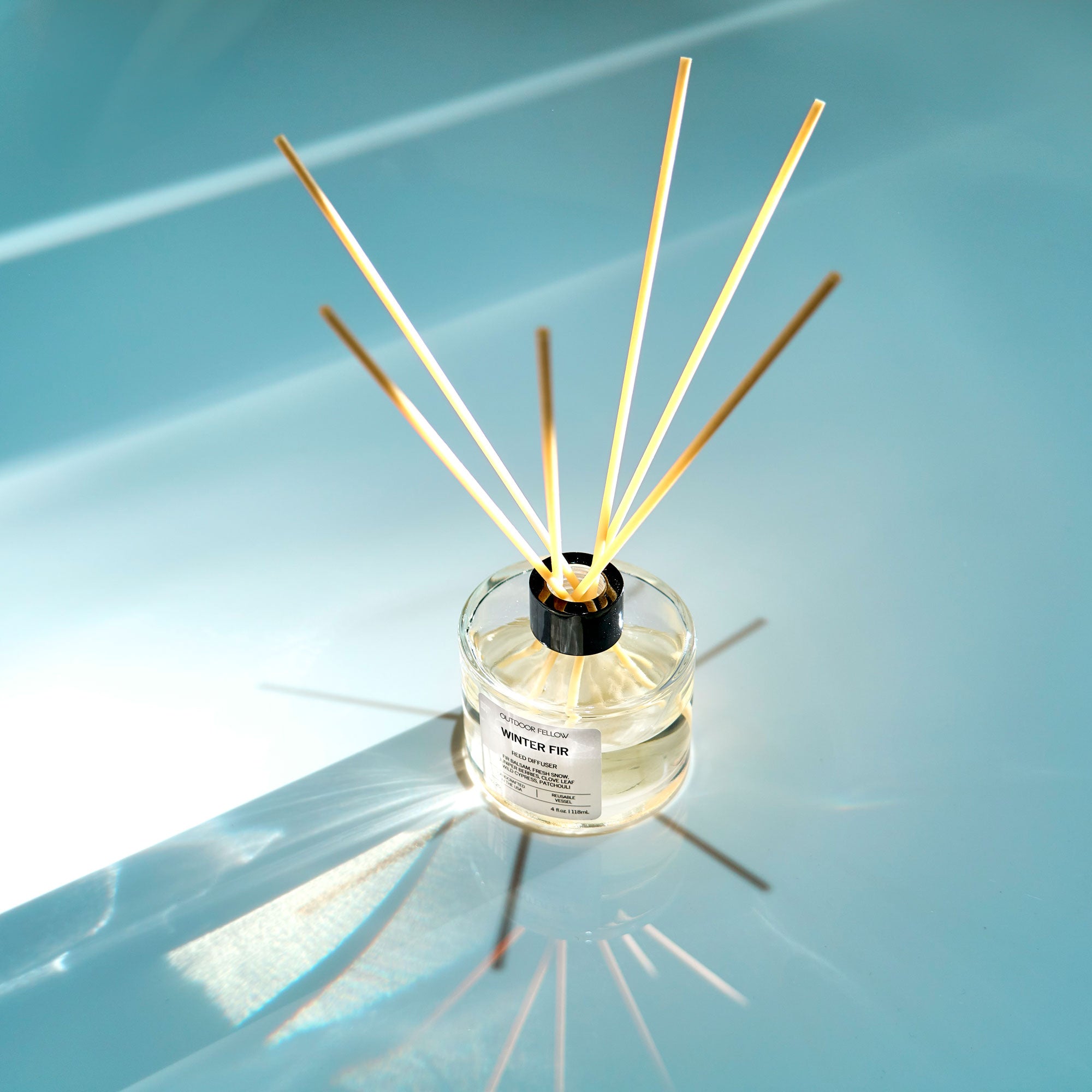 Winter Fir reed diffuser on reflective bue surface that looks like ice in the sun