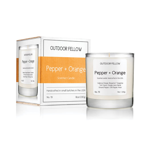 Pepper and Orange scented candle next to packaging on white background