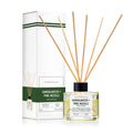 Outdoor Fellow Sandalwood + Pine Needle reed diffuser with packaging box, featuring a clear glass bottle, natural reeds, and a label listing scent notes including sweet orange, pine needle, and cedarwood.