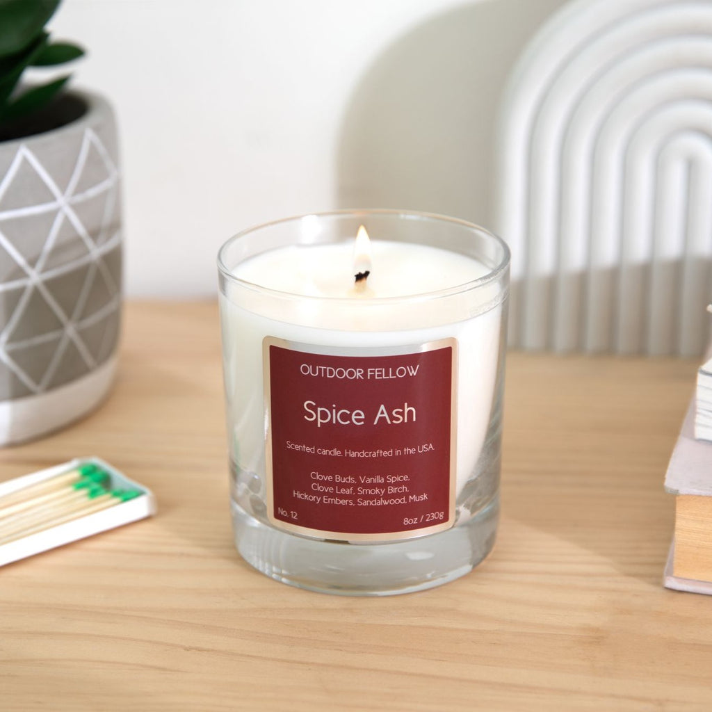 Spice Ash scented candle on wooden table with a book of matches