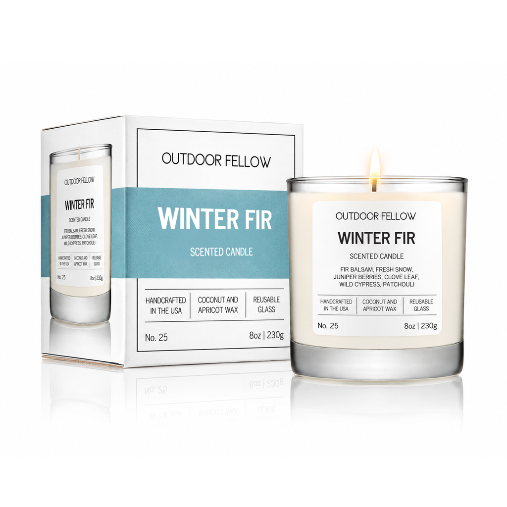 Outdoor Fellow Winter Fir scented candle in a clear glass jar with a white label and wick, shown next to its white and light blue retail box on a clean white background.