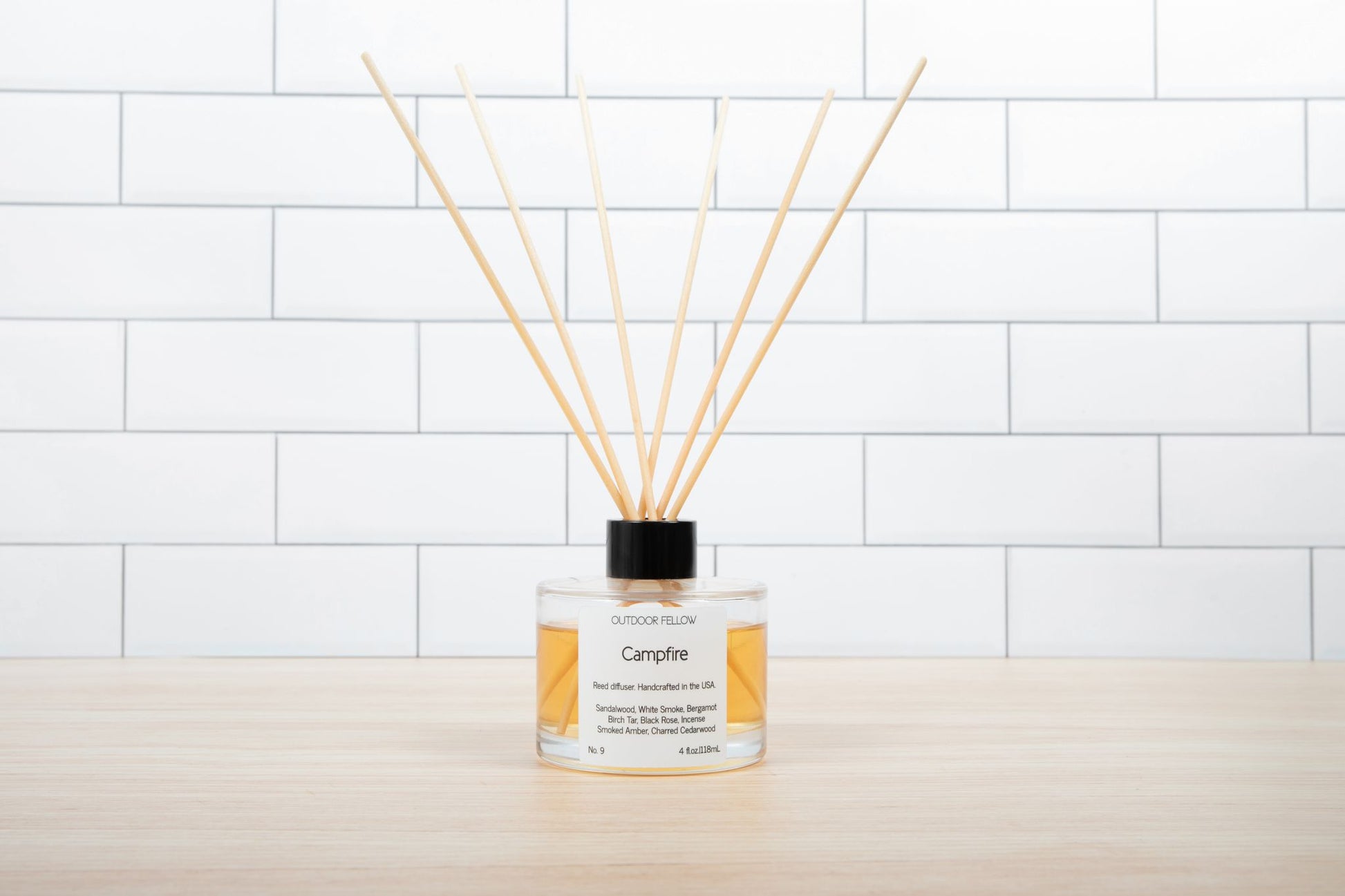 Campfire reed diffuser on a butcher block surface with white subway tile in the background