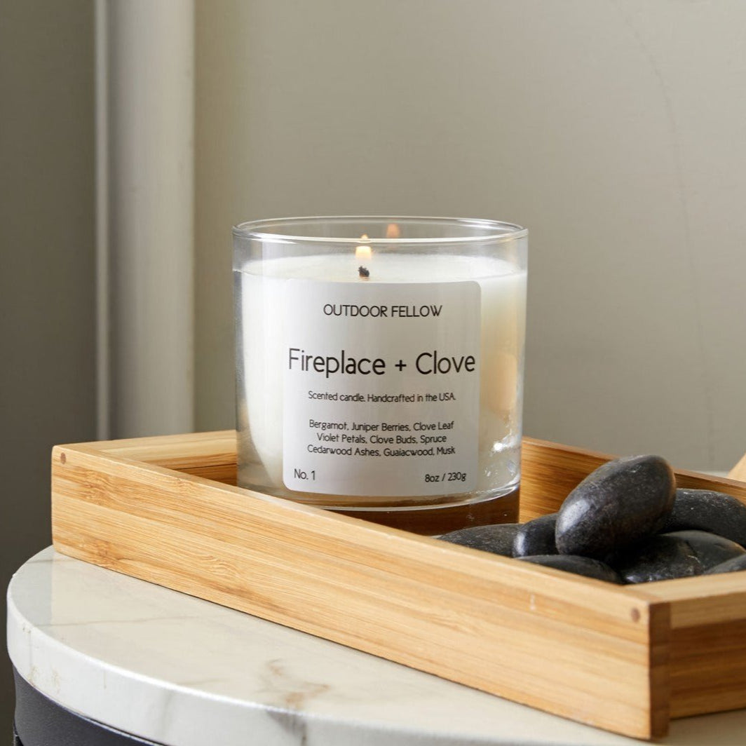 Fireplace + Clove candle on a wooden tray next to a bed