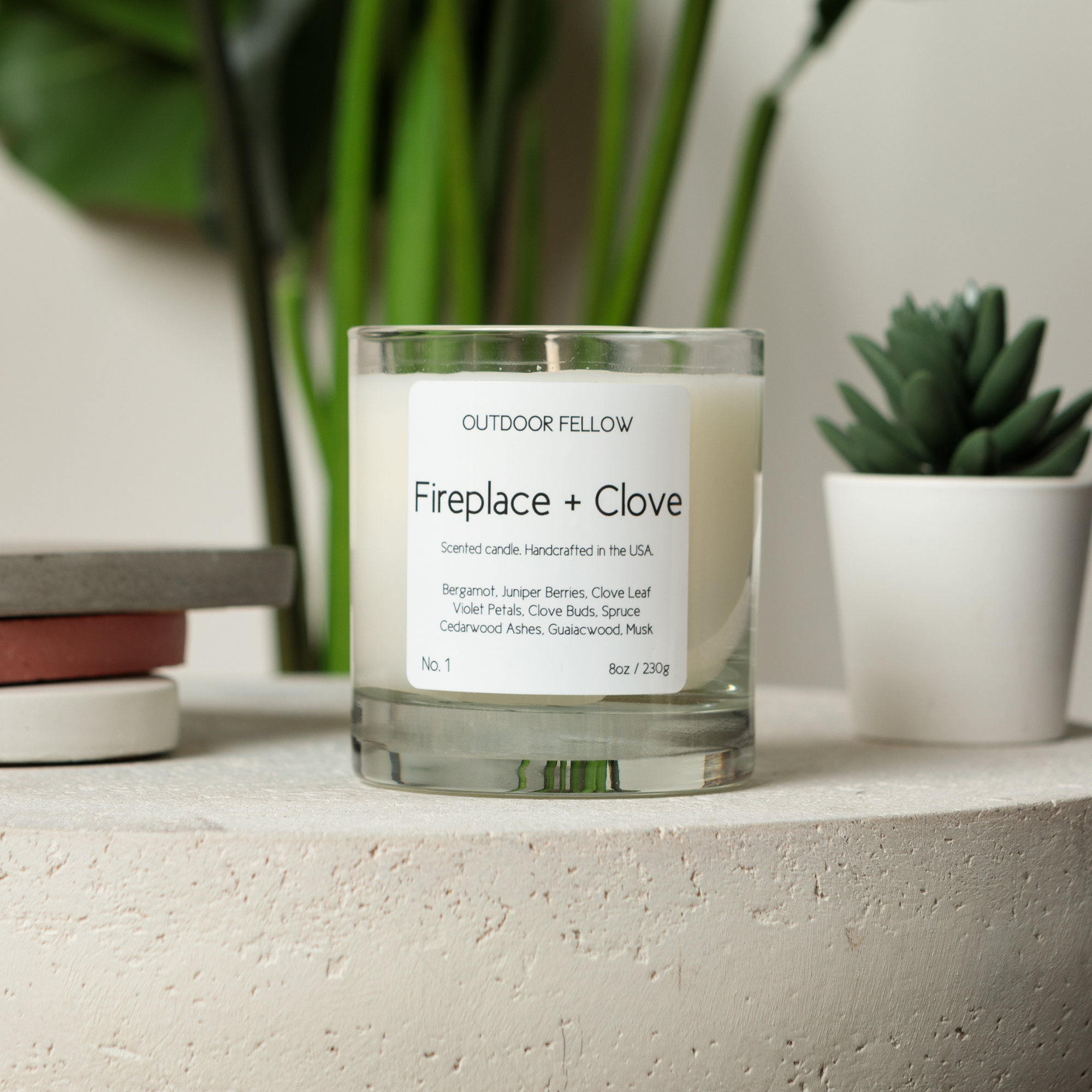 Fireplace and Clove scented candle on concrete surface next to objects and succulents