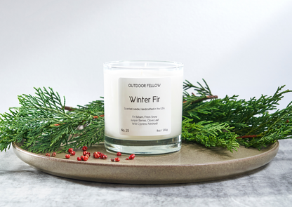 Winter Fir scented candle on plate surrounded by cypress needles and red berries