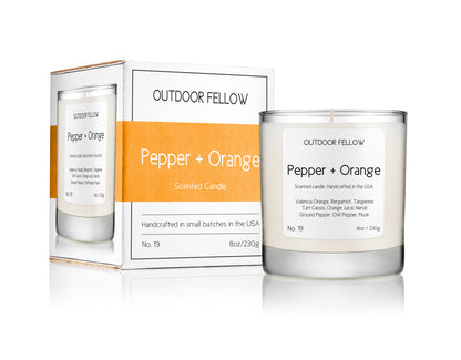 Pepper and Orange scented candle next to packaging on white background