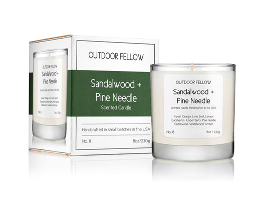 Sandalwood and Pine Needle scented candle next to packaging on white background
