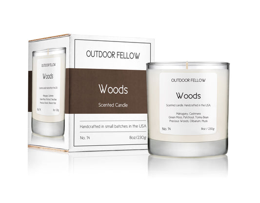 Woods scented candle next to packaging on white background