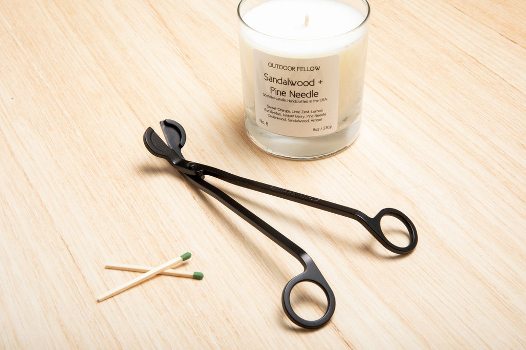 Outdoor Fellow wick trimmer sitting next to a candle and matches